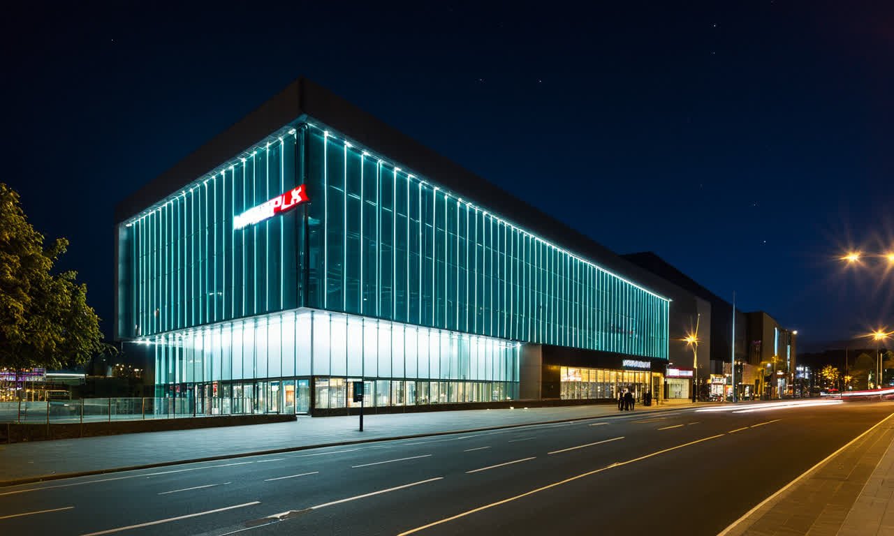 Lit multiplex cinema at night, glass facade glowing teal — the kind of mainstream venue that rarely screens Australian films